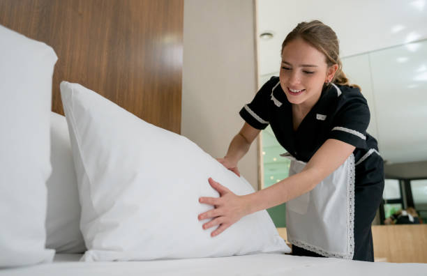 Beautiful housekeeper making the bed at a hotel looking happy and smiling Beautiful housekeeper making the bed at a hotel looking happy and smiling